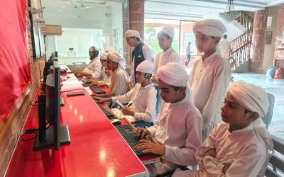 Young students in traditional attire using computers at Mohsin Quran Foundation.
