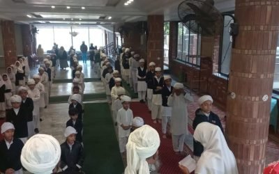 Students in white prayer attire praying at Mohsin Quran Foundation.