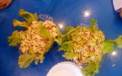 Colorful salad arrangements with lettuce and vegetables on a blue table.